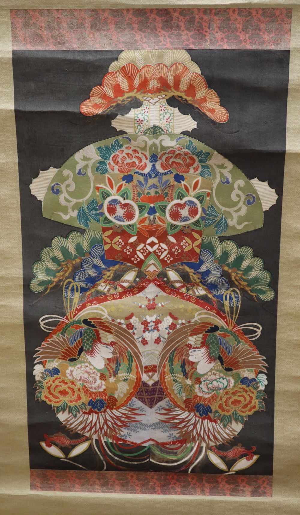 A Japanese scroll decorated with a design of bright multi-coloured motifs creating a central cartouche, together with another scroll wi